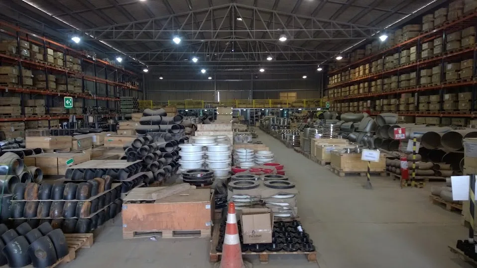 Galpão industrial com racks e paletes de tubos metálicos